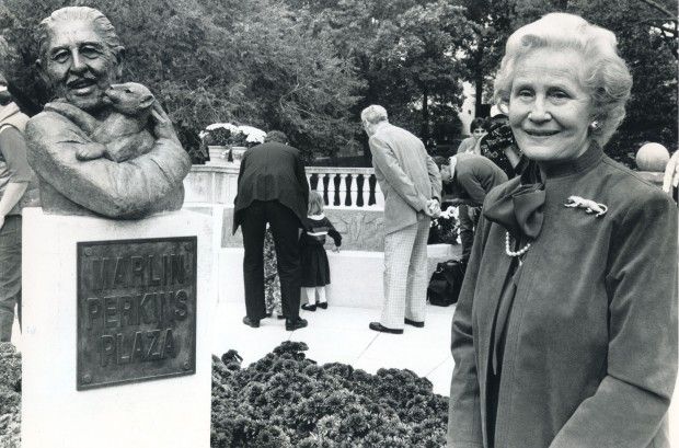 Carol Perkins stands near bust of her husband in Forest Park